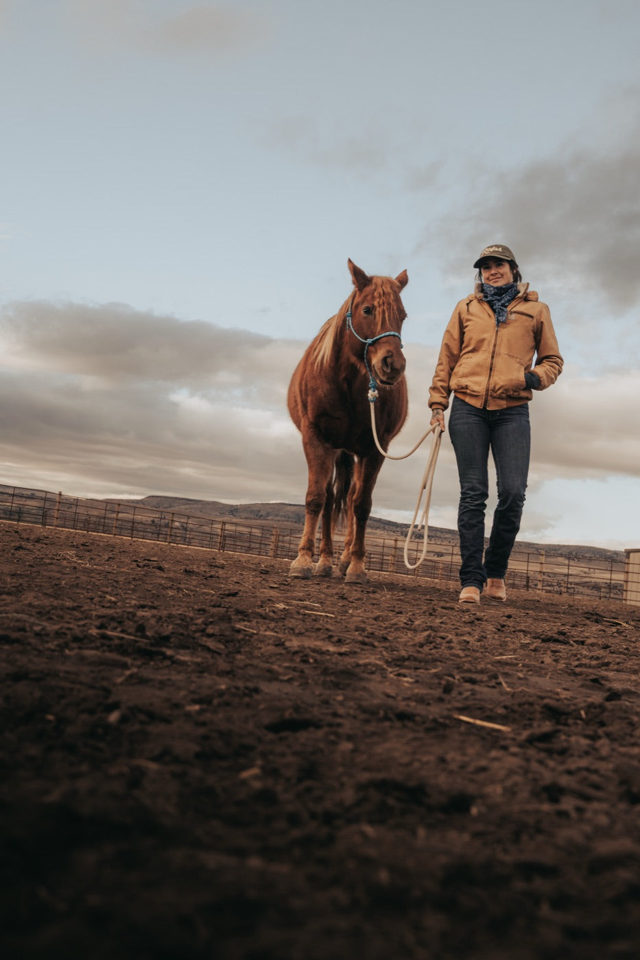 Woman walking horse through barn alley